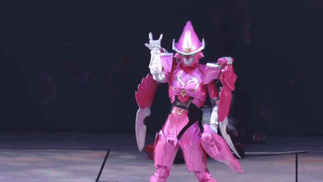 a pink robot is standing on a stage with a purple background