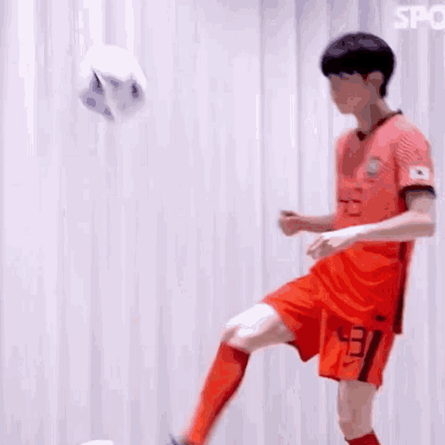 a man in a red shirt is playing soccer with another man .