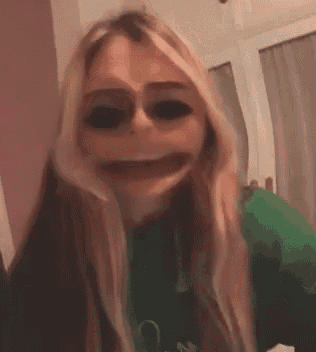 a woman wearing a green shirt is making a funny face with her mouth open .