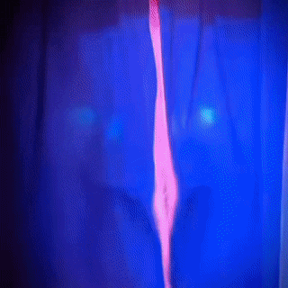 a woman in a blue and pink dress is behind a blue curtain