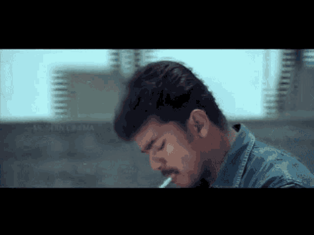 a man is smoking a cigarette in front of a building that says martin cinema