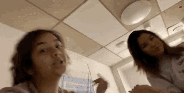 two women are standing next to each other in a room and one of them is wearing a shirt that says dark
