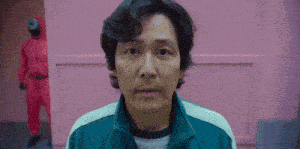 a man in a green jacket is standing in front of a pink wall in a room .