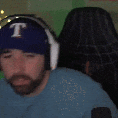 a man wearing headphones and a blue hat with the letter t on it says we out here cooking