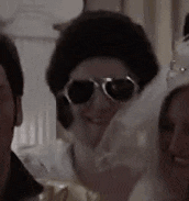a woman wearing sunglasses and a fur hat is smiling in a group of people .