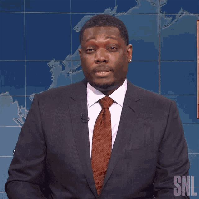 a man in a suit and tie is standing in front of a snl logo