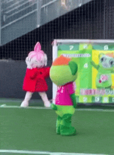 two mascots are standing on a soccer field with a sign that says " welcome "