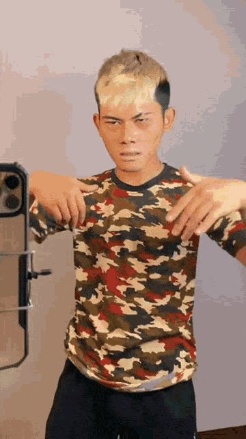 a man in a camouflage shirt is standing in front of a mirror
