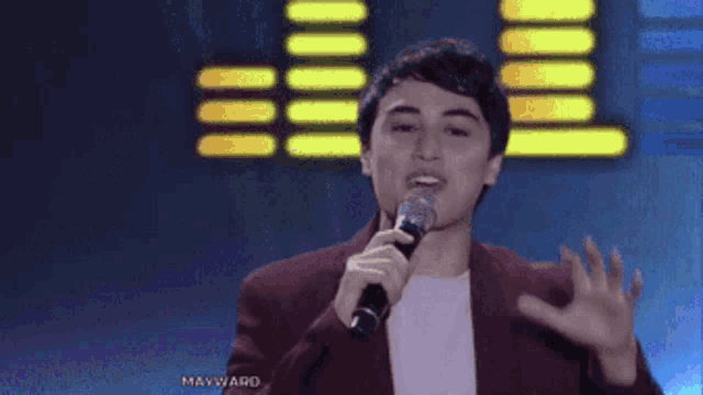 a young man singing into a microphone with the words mayward behind him