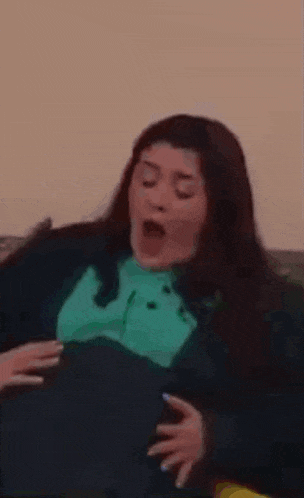a woman is sitting on a couch with her mouth open and yawning .