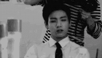 a man in a suit and tie is getting his hair done .