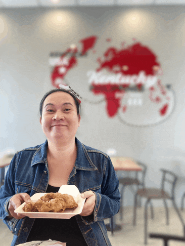a woman is holding a tray of food in front of a kentucky sign