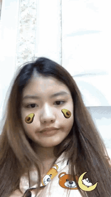 a girl with avocados on her face is wearing a teddy bear shirt