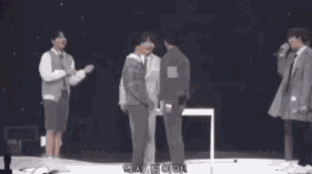 a group of young men are hugging each other and one of them is wearing a suit and tie .