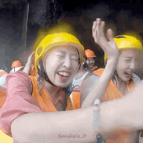 a woman wearing a yellow helmet is giving a high five to another woman