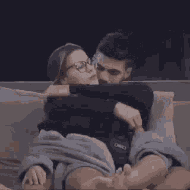 a man and a woman are laying on a couch hugging each other .