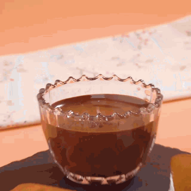 a glass bowl filled with chocolate sauce is on a table