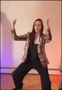 a woman in a snake print jacket is dancing with her hands in the air