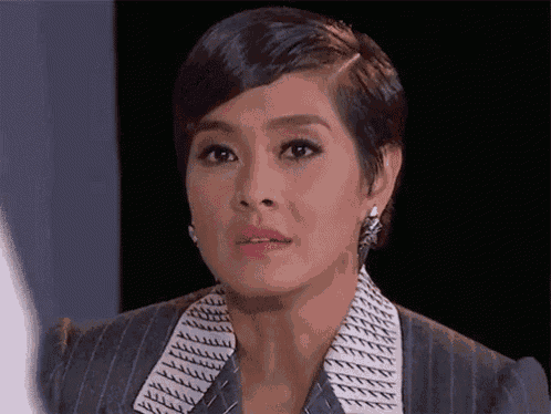 a woman with short hair and earrings is wearing a suit and a striped shirt .