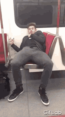 a man sitting on a train with his legs crossed