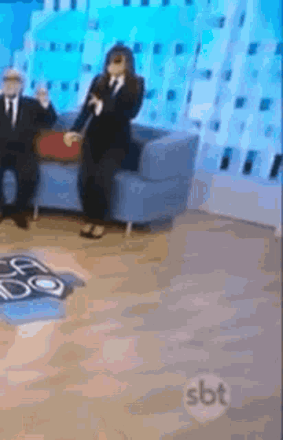 a man and a woman are sitting on a couch in front of a sbt logo