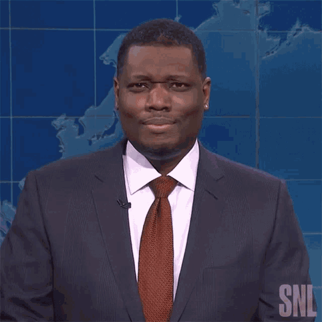 a man in a suit and tie with the snl logo on his shirt
