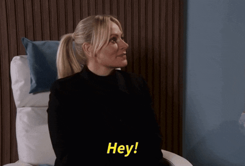 a woman sitting in a chair says hey in yellow