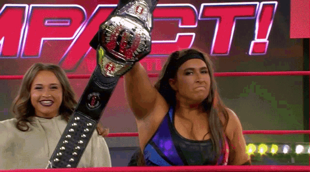 a woman in a wrestling ring is holding a championship belt