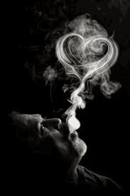 a man is smoking a cigarette with smoke coming out of his mouth in the shape of a heart .