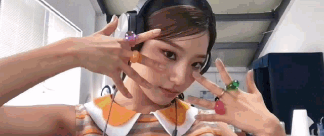 a woman wearing headphones and rings is making a peace sign .