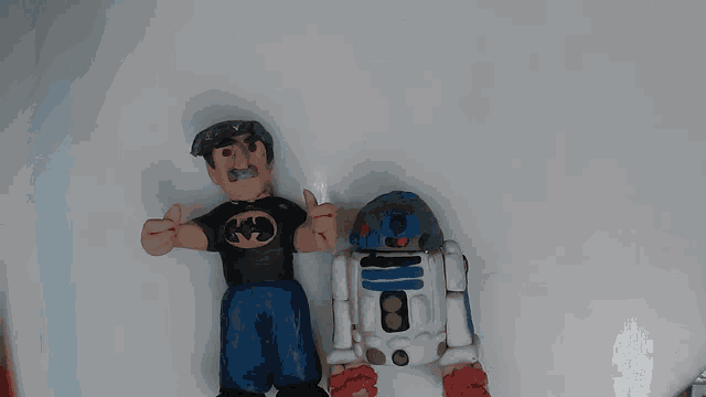 a man in a batman shirt is standing next to a robot