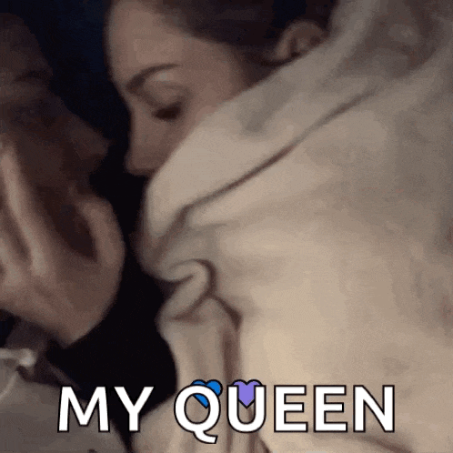 a couple is kissing under a blanket with the words `` my queen '' written on it .