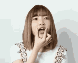 a young woman is making a funny face with her finger in her mouth