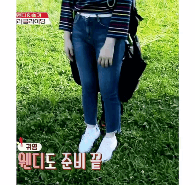 a woman is standing in the grass with a backpack on her back .