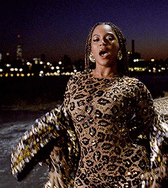 a woman in a leopard print dress is standing in front of a city skyline