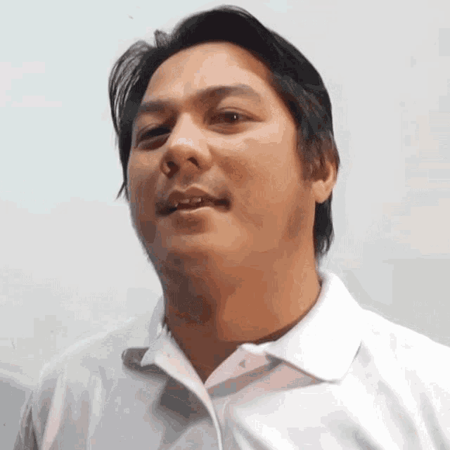 a man is wearing a white shirt and making a funny face