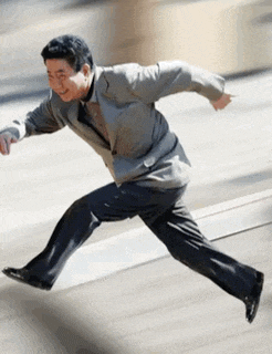 a man in a suit and tie is running on a street