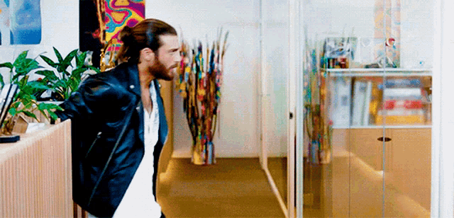 a man in a black leather jacket is walking down a hallway .