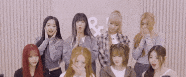 a group of young girls are standing next to each other with their hands on their faces .