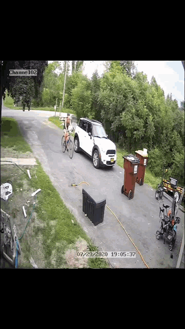 a white mini cooper is parked on the side of the road next to some trash cans