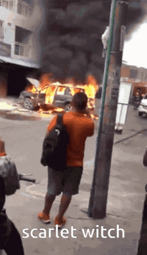 a man taking a picture of a car on fire with scarlet witch written on the bottom