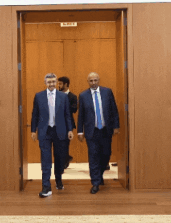 two men in suits are walking through a doorway with a sign that says exit on it