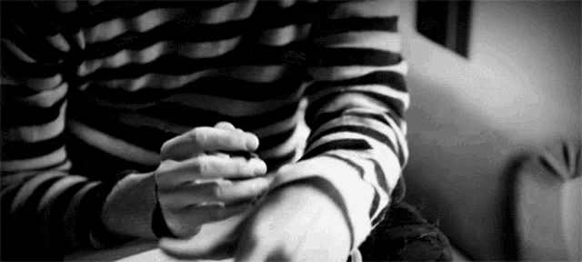 a black and white photo of a person cutting their arm .