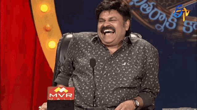 a man is laughing in front of a mvr mall sign