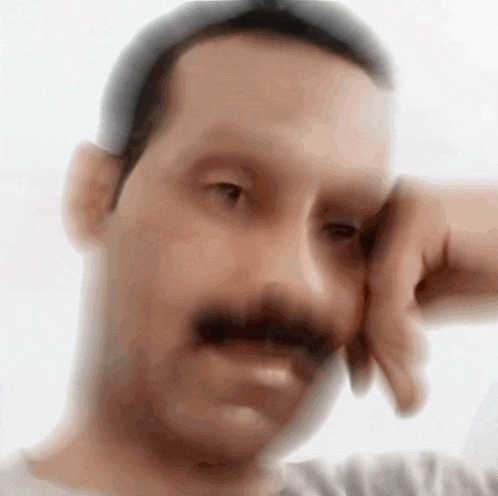 a blurry picture of a man 's face with his hand on his face