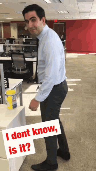 a man in an office with a sign that says " i dont know is it "