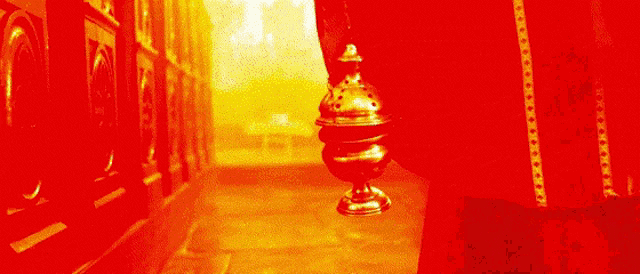 a gold object is hanging from a chain in front of a red background