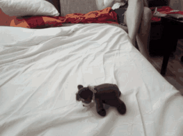 a stuffed animal laying on a bed with a white blanket