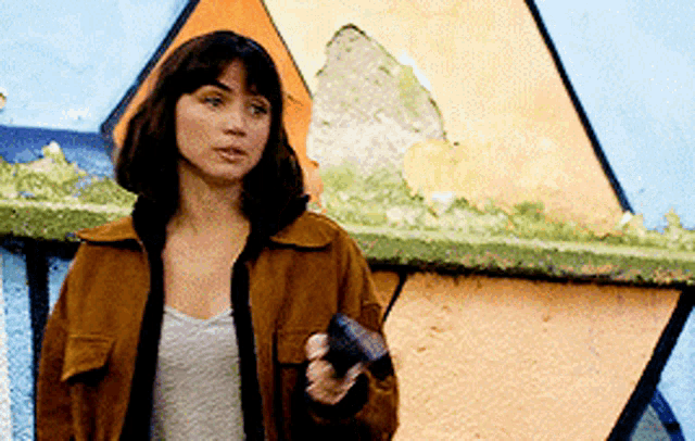 a woman in a brown jacket is holding a gun in her hand