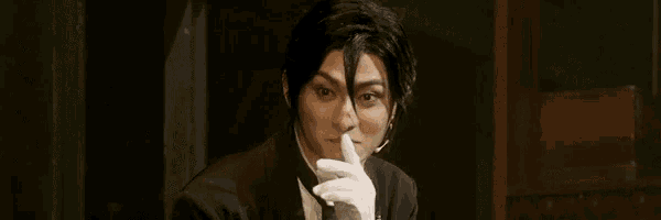 a man wearing white gloves is holding a piece of paper to his face .